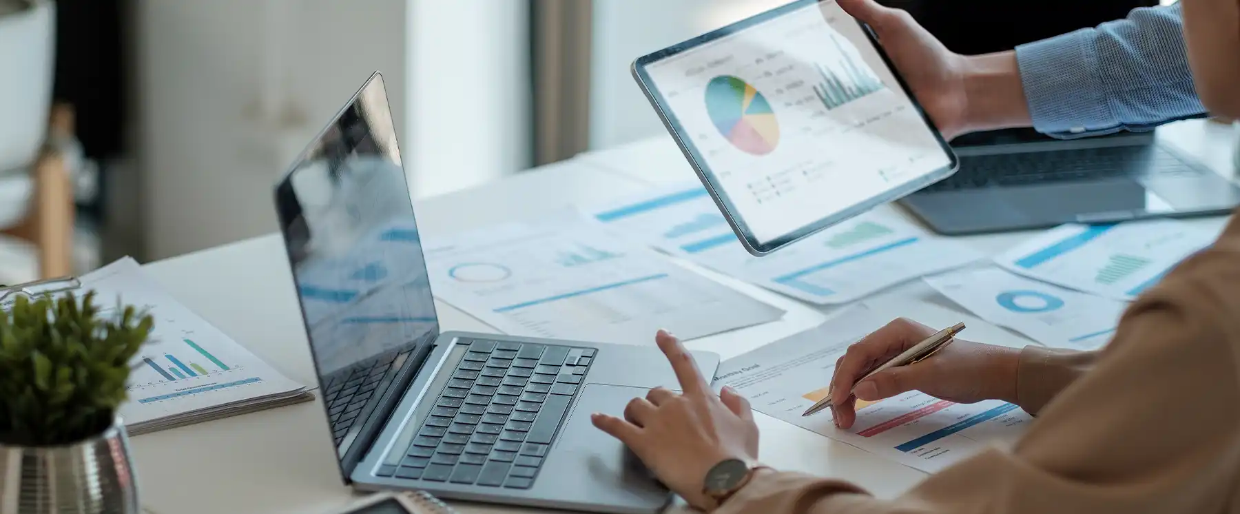 Business professionals analyzing financial charts and data on tablets and laptops